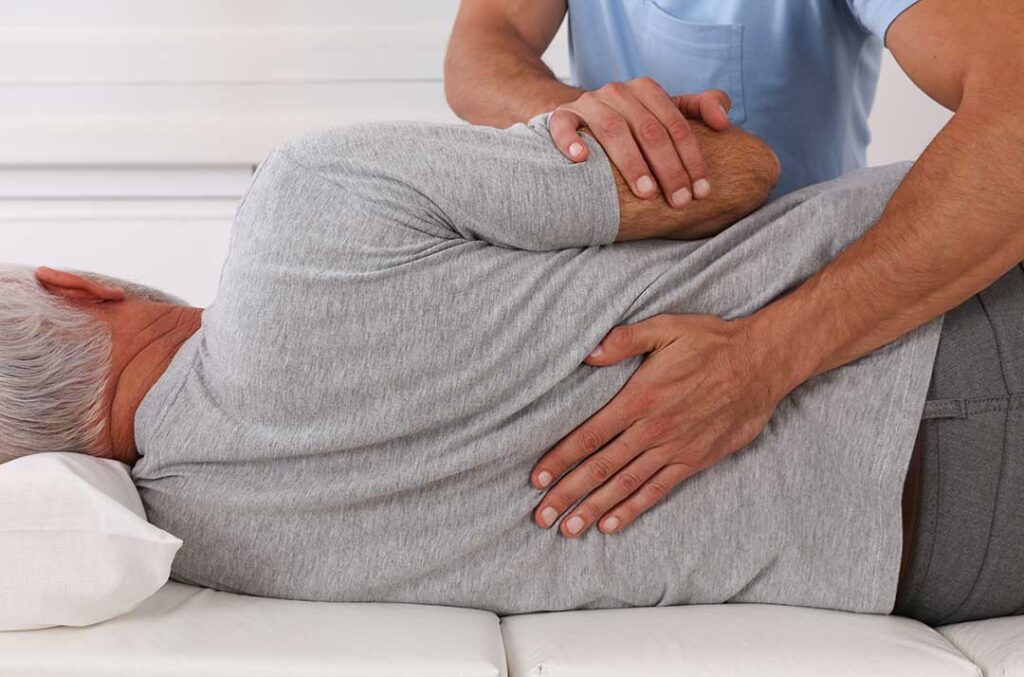 A person stretching gently at home on a yoga mat with supportive pillows nearby.