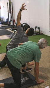 Older adult performing gentle knee exercises beside a chair with a resistance band nearby.