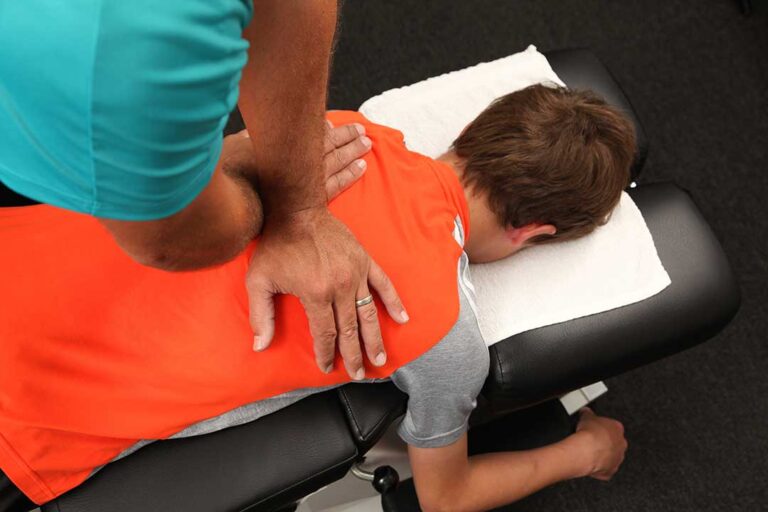 Person practicing slow breathing while seated beside a treatment table, with relaxed posture and soft natural light.
